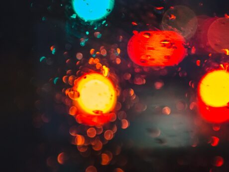 Abstract depiction of car brake lights at night time, viewed through wet glass.