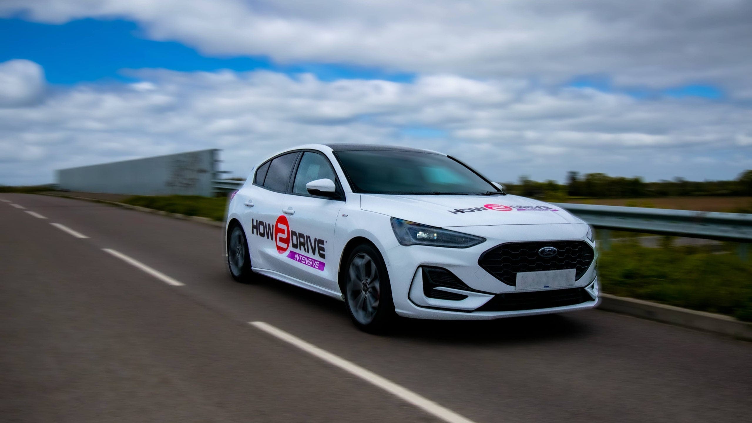 Low angle shot of one of the cars we use for intensive driving courses driving towards the camera.